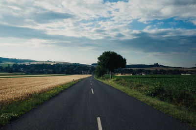 Road amidst field against sky