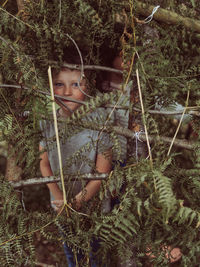 Caucasian child in a hut made of branches and leaves