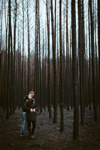 Full length of man standing amidst trees in forest