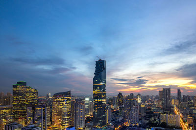 Illuminated modern buildings against sky in city