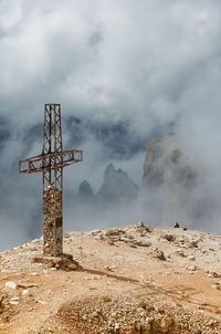 Cross on mountain against cloudy sky