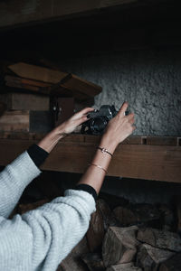 Cropped hands of woman putting camera on shelf