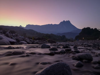 Rocks on beach against sky during sunset