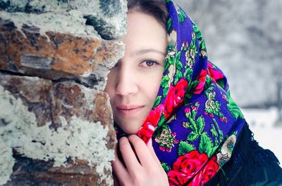 Portrait of beautiful young woman wearing scarf while standing by wall