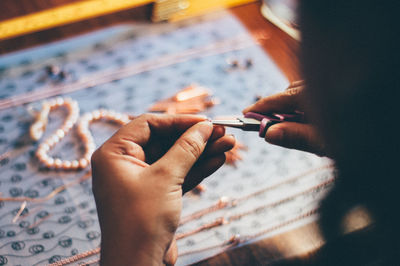 High angle view of woman making necklace