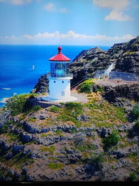 Lighthouse amidst sea and buildings against sky