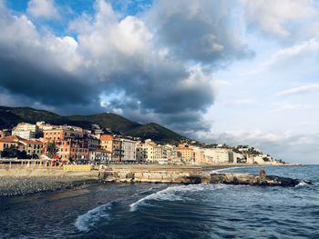 Buildings by sea against sky in city