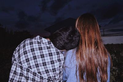 Rear view of couple kissing against sky