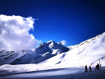 People on snowcapped mountain against sky