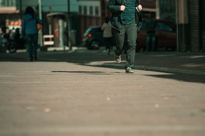 Low section of man walking on street in city