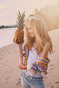 Girl holding pineapple on beach