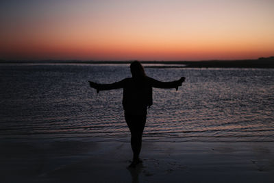 Silhouette man on beach against sky during sunset