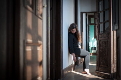 Side view of young woman looking through window