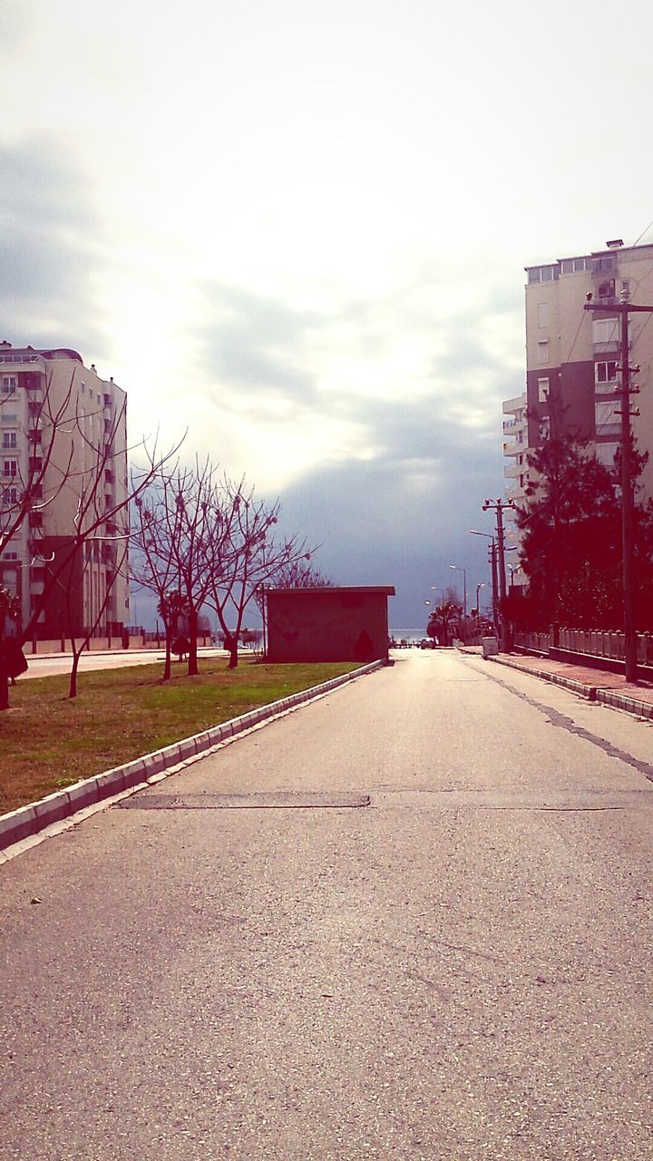 building exterior, architecture, the way forward, built structure, sky, diminishing perspective, street, transportation, cloud - sky, vanishing point, road, empty, road marking, surface level, cloudy, city, outdoors, tree, long, cloud