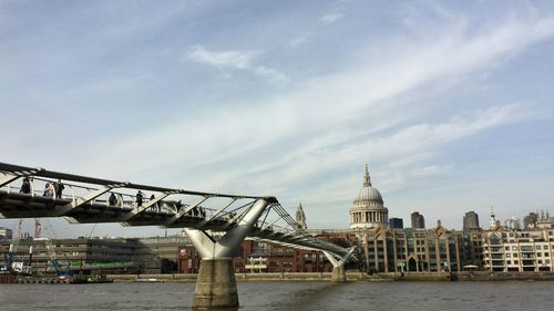 View of suspension bridge over river against cloudy sky