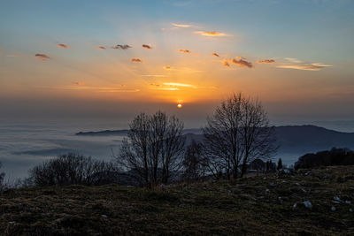 Scenic view of bergamo fog covered against sky during sunset