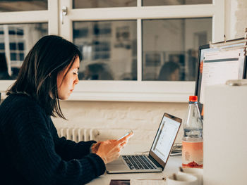 Woman using mobile phone in office