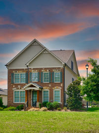 House on field against sky during sunset