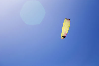 Low angle view of person paragliding against clear blue sky