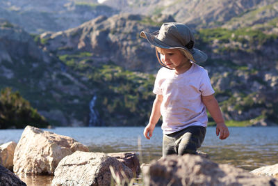 Rear view of boy on rock at shore