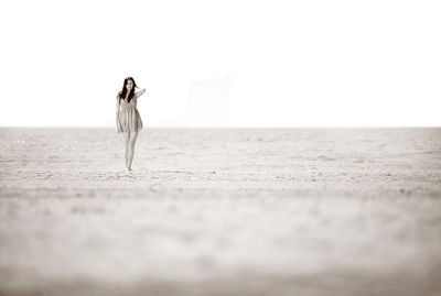 Woman standing at beach against sea and sky during sunny day