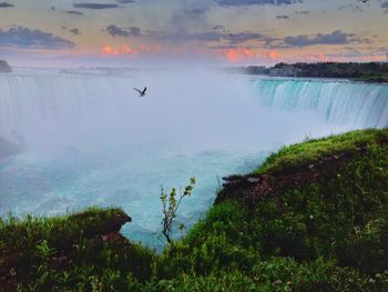 Scenic view of waterfall against sky at sunset
