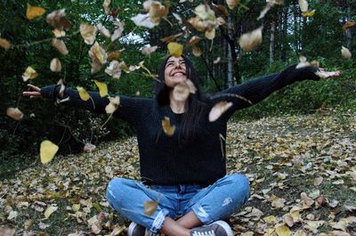 Young woman sitting on autumn leaves