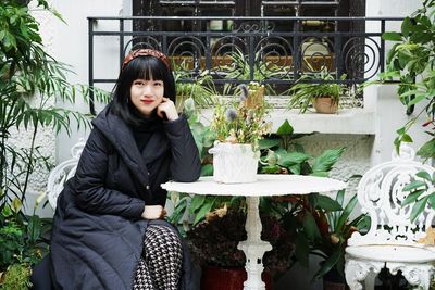 Portrait of woman sitting on potted plant