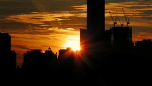 Silhouette city against sky during sunset