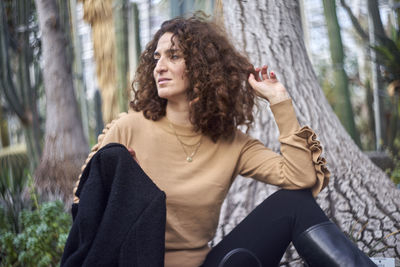 Woman sitting by tree trunk at park