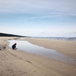 Child playing at beach against sky