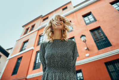 Low angle view of smiling young woman standing outside building