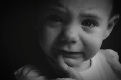 Close-up portrait of cute baby girl against black background