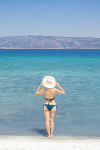 Full length rear view of woman standing at beach