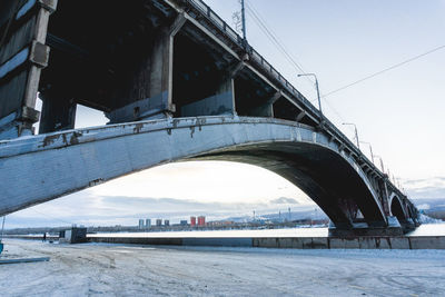 Arch bridge over river in city against sky