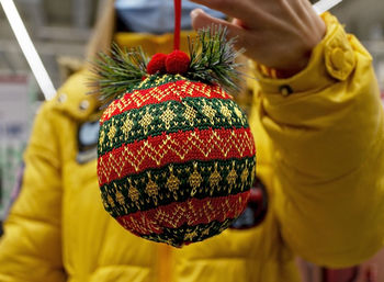 Red green knitted christmas ball in female hand close-up. christmas and new year gift