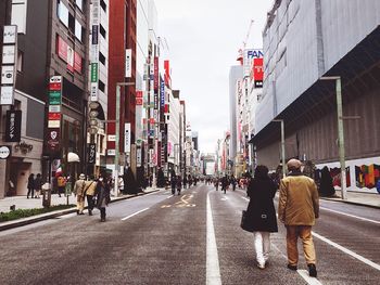 People walking on road amidst buildings in city