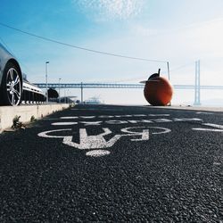 Text on road against sky on sunny day