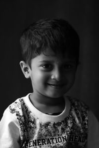 Portrait of smiling boy against black background