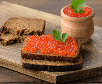 Red salmon caviar lies on a piece of rye bread. brown wooden table