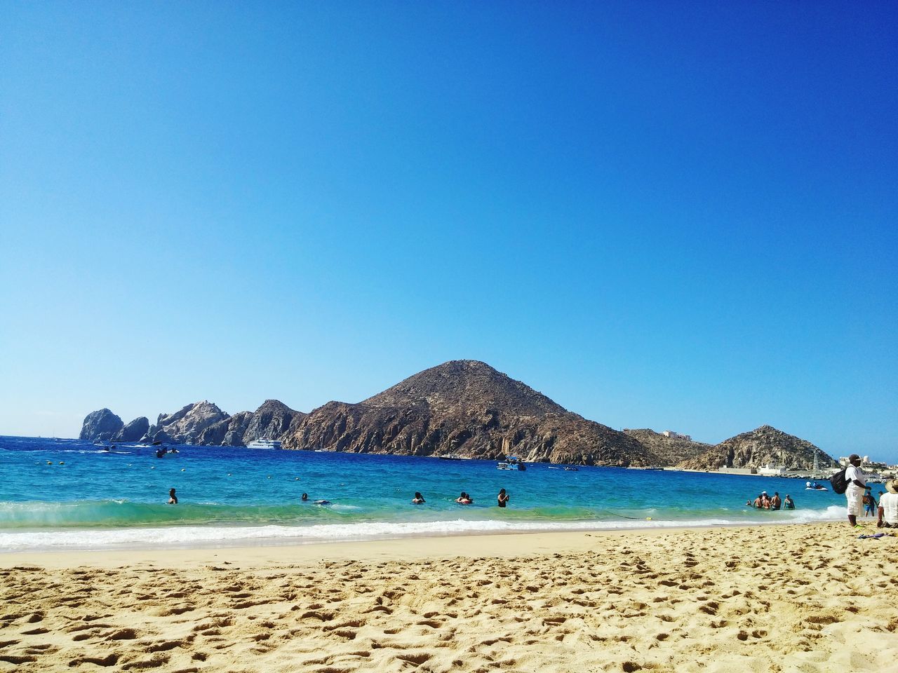 beach, sea, blue, water, clear sky, sand, copy space, shore, mountain, scenics, tranquil scene, tranquility, beauty in nature, vacations, nature, coastline, incidental people, idyllic, tourism, day