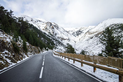 Road amidst snowcapped mountains against sky