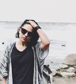 Young man wearing sunglasses standing at sea shore