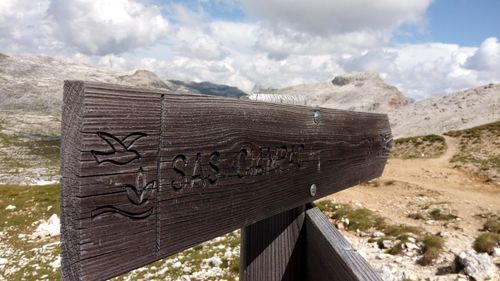 Text on stone wall against cloudy sky