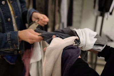 Midsection of salesman showing clothes to customer at store