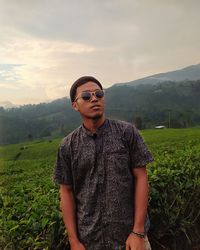 Young man wearing sunglasses standing on field