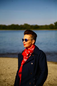 Woman wearing sunglasses while standing by lake 