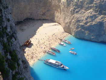 Shipwreck in the sand of a blue sea beach with other boats betwenn white montains - greece
