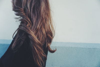 Side view of woman standing by retaining wall against sky