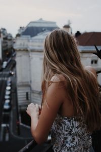 Rear view of woman standing at balcony